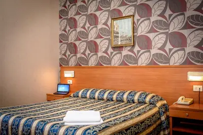 a bedroom with a bed with a patterned wall at Hotel Emmaus in Rome