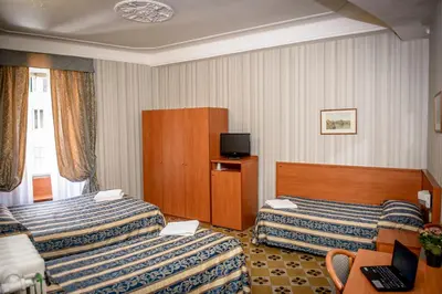 a hotel room with two beds and a television at Hotel Emmaus in Rome