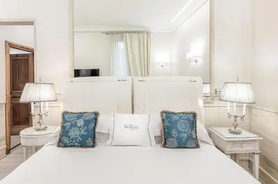 a bedroom with a white bed with blue pillows at Hotel Barocco in Rome
