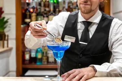a bartender preparing a blue drink in a martini glass at Hotel Barocco in Rome