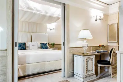 a bedroom with a bed and a desk with a lamp at Hotel Barocco in Rome
