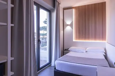 a bedroom with a bed and a large window at Garner Hotel Rome Aurelia by IHG in Rome