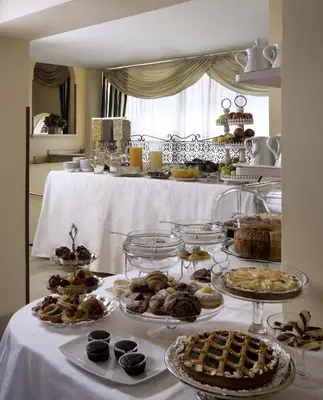 a table filled with different types of pastries and desserts at Colonna Palace Hotel in Rome
