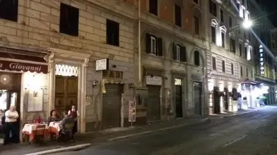 a city street at night with people sitting at tables at B&B Rome With Love in Rome