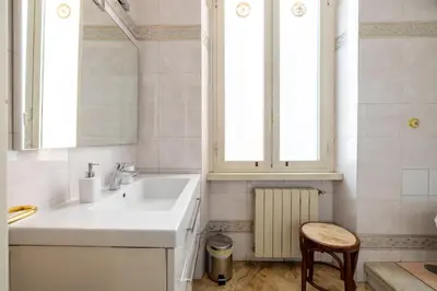 a white bathroom with a sink and a stool at House Montebello in Rome