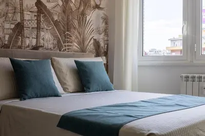a bedroom with a bed with blue pillows and a window at Radio Hotel in Rome