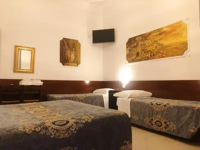 a room with three beds and a painting on the wall at Hostel Cosmos in Rome