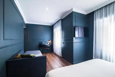 a bedroom with blue walls and a bed and a chair at Seven Suites in Rome