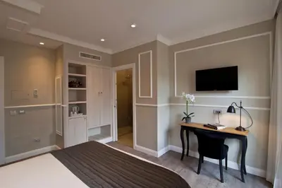 a bedroom with a desk and a tv on the wall at Seven Suites in Rome