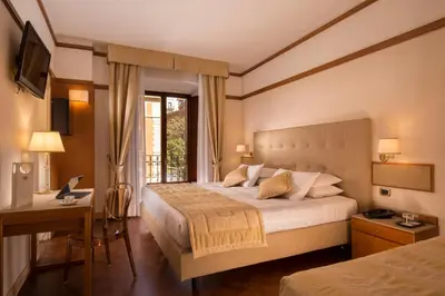 a bedroom with two beds and a desk and a television at La Residenza in Rome