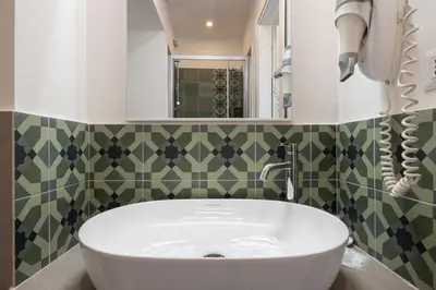 a bathroom with a white tub and green tiles at New Morpheus Rooms in Rome