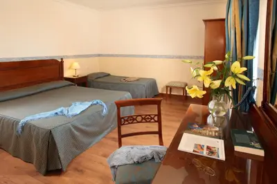 a bedroom with a bed and a table with a vase of flowers at Hotel Alessandrino in Rome