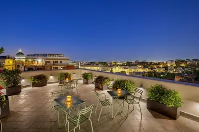 a rooftop patio with tables and chairs and a view of the city at Hotel Alessandrino in Rome