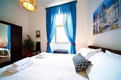 a bedroom with a bed with blue curtains and a window at Vetrina Holidays Apartment Navona in Rome