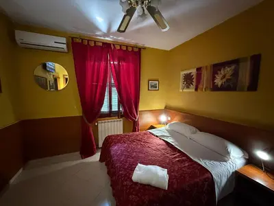 a bedroom with a bed with red sheets and a window at Viennese Due in Rome