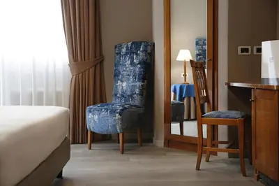 a bedroom with a blue chair and a mirror at BeYou Hotel Ponte Milvio in Rome