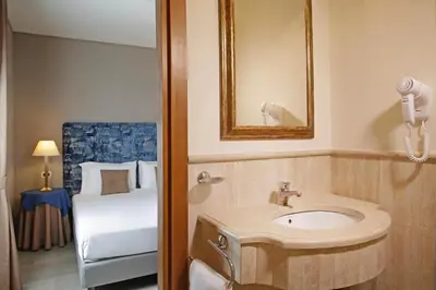 a bathroom with a sink and a bed at BeYou Hotel Ponte Milvio in Rome