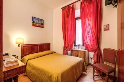 a bedroom with a bed and a desk and a window at Hotel Gea Di Vulcano in Rome