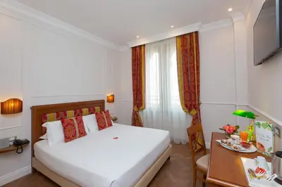 a hotel room with a white bed and a table at Hotel Milton Roma in Rome