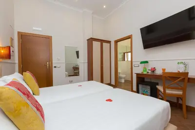 a bedroom with two beds and a desk and a television at Hotel Milton Roma in Rome