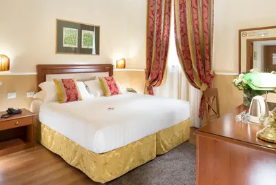 a bedroom with a large white bed with red curtains at Hotel Milton Roma in Rome