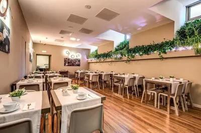 a restaurant with tables and chairs and plants on the wall at Al Manthia Hotel - Gruppo Trevi Hotels in Rome