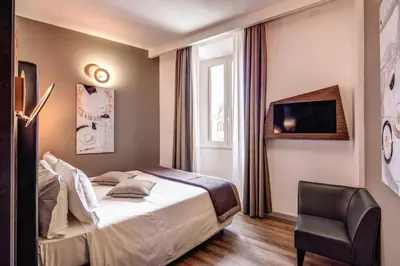 a hotel room with a bed and a chair at Al Manthia Hotel - Gruppo Trevi Hotels in Rome
