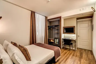a hotel room with a bed and a desk at Al Manthia Hotel - Gruppo Trevi Hotels in Rome