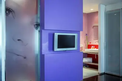 a room with a purple wall with a tv on it at Hotel Ariston in Rome