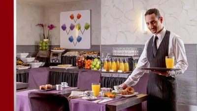 a man in a restaurant holding a tray of food at Hotel Ariston in Rome