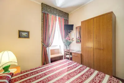 a bedroom with a bed and a dresser and a window at Buonarroti Home in Rome