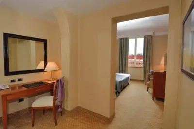 a hotel room with a desk and a bed and a mirror at LH Hotel Lloyd Roma in Rome