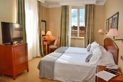a hotel room with a bed and a flat screen tv at LH Hotel Lloyd Roma in Rome