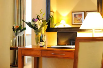 a desk with a laptop and a vase of flowers at LH Hotel Lloyd Roma in Rome