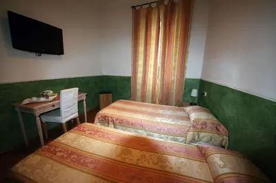 a bedroom with two beds and a table and a television at Residenza Ki in Rome