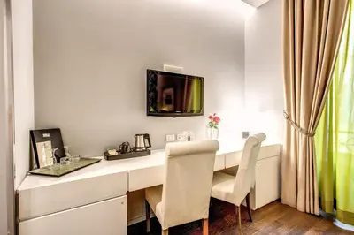a room with a desk with chairs and a television on the wall at Roma Boutique Hotel in Rome