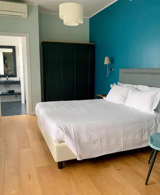 a bedroom with a large white bed and a blue wall at Hotel Fenix in Rome