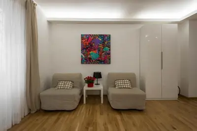 a living room with two chairs and a painting on the wall at Saint Peter Apartment in Rome