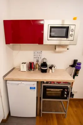 a small kitchen with red cabinets and a microwave at Saint Peter Apartment in Rome