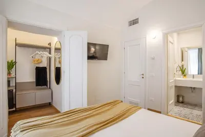 a white bedroom with a bed and a mirror at 94Rooms Vatican Guest House- Scipioni in Rome
