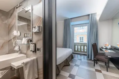 a hotel room with a bed and a sink and a desk at Best Western Plus Hotel Universo in Rome