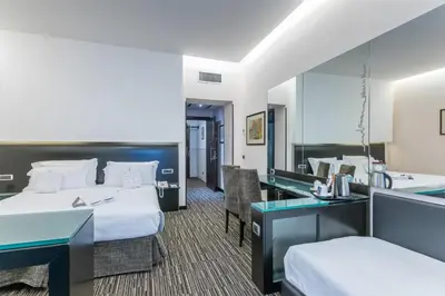 a hotel room with a bed and a desk and a mirror at Best Western Plus Hotel Universo in Rome