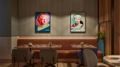 a restaurant with a table with four portraits on the wall at Hilton Garden Inn Rome Colosseum in Rome