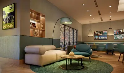 a waiting room with a couch and a table and chairs at Hilton Garden Inn Rome Colosseum in Rome