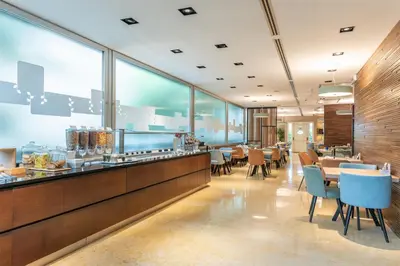 a restaurant with tables and chairs and large windows at Hilton Garden Inn Rome Claridge in Rome