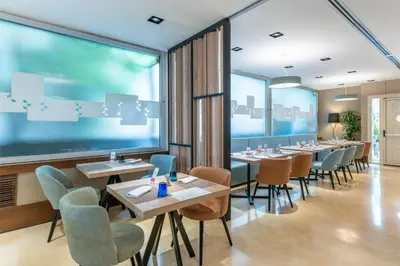 a restaurant with tables and chairs and a large window at Hilton Garden Inn Rome Claridge in Rome