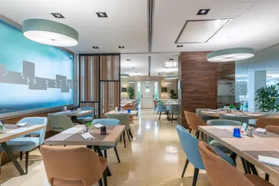 a restaurant with tables and chairs and a large window at Hilton Garden Inn Rome Claridge in Rome