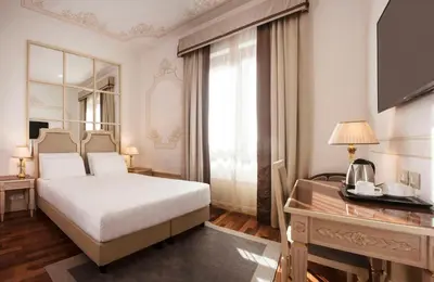 a bedroom with a bed and a desk and a mirror at Radisson Blu GHR Rome in Rome