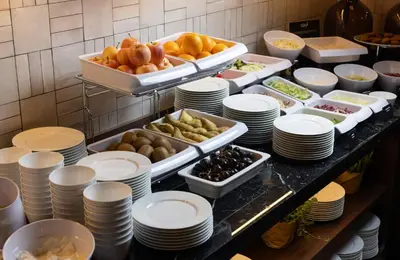a buffet with plates and food on a table at NYX Hotel Rome by Leonardo Hotels in Rome