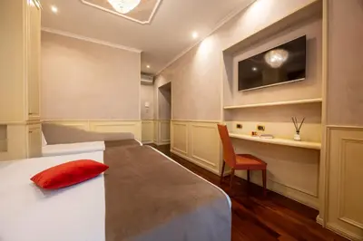 a bedroom with a bed with a red pillow and a desk at Al Viminale Hill Inn & Hotel in Rome